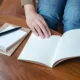Gros plan sur les mains d'une personne étudiant à l'aide d'un cahier et d'un bloc-note