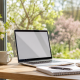 Espace de travail lumineux au printemps avec ordinateur portable, carnet et fleurs près d’une grande fenêtre pour illustrer un projet de formation